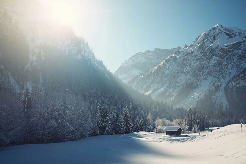 Verschneites Tal mit Hütte im Gegenlicht